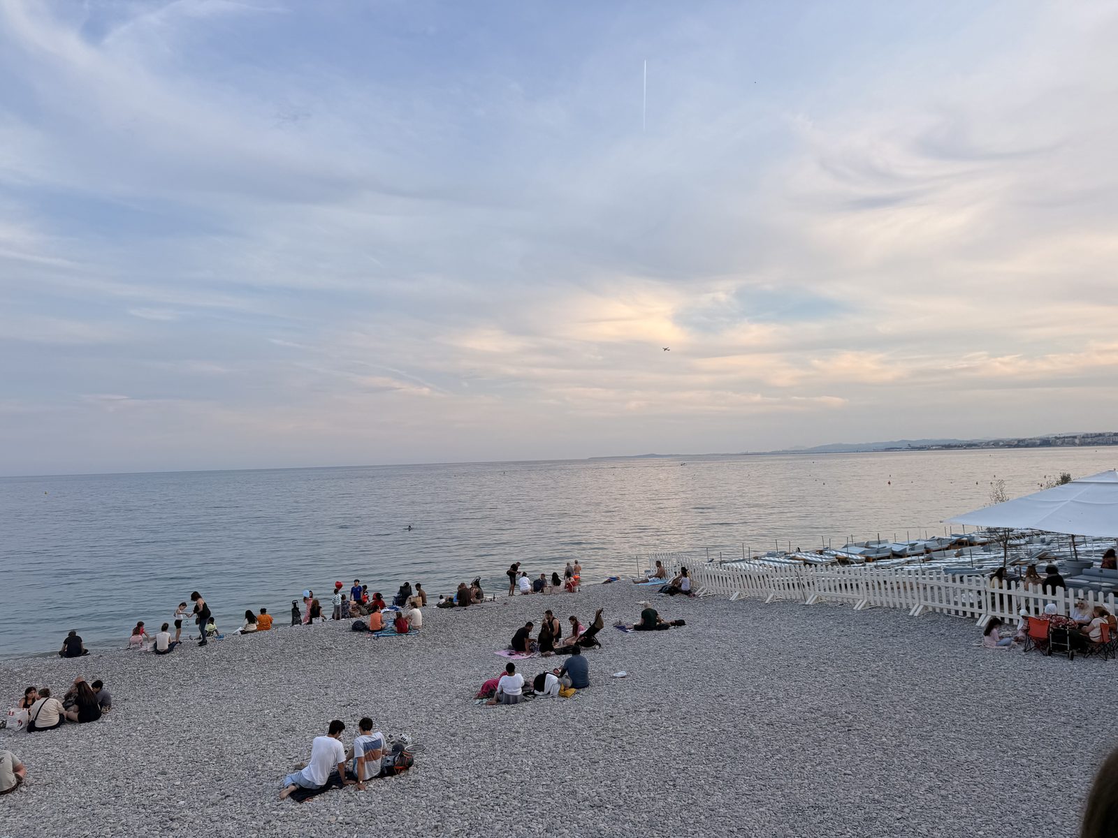 The pebble beach at Nice at dusk, the sky pink over a flat sea