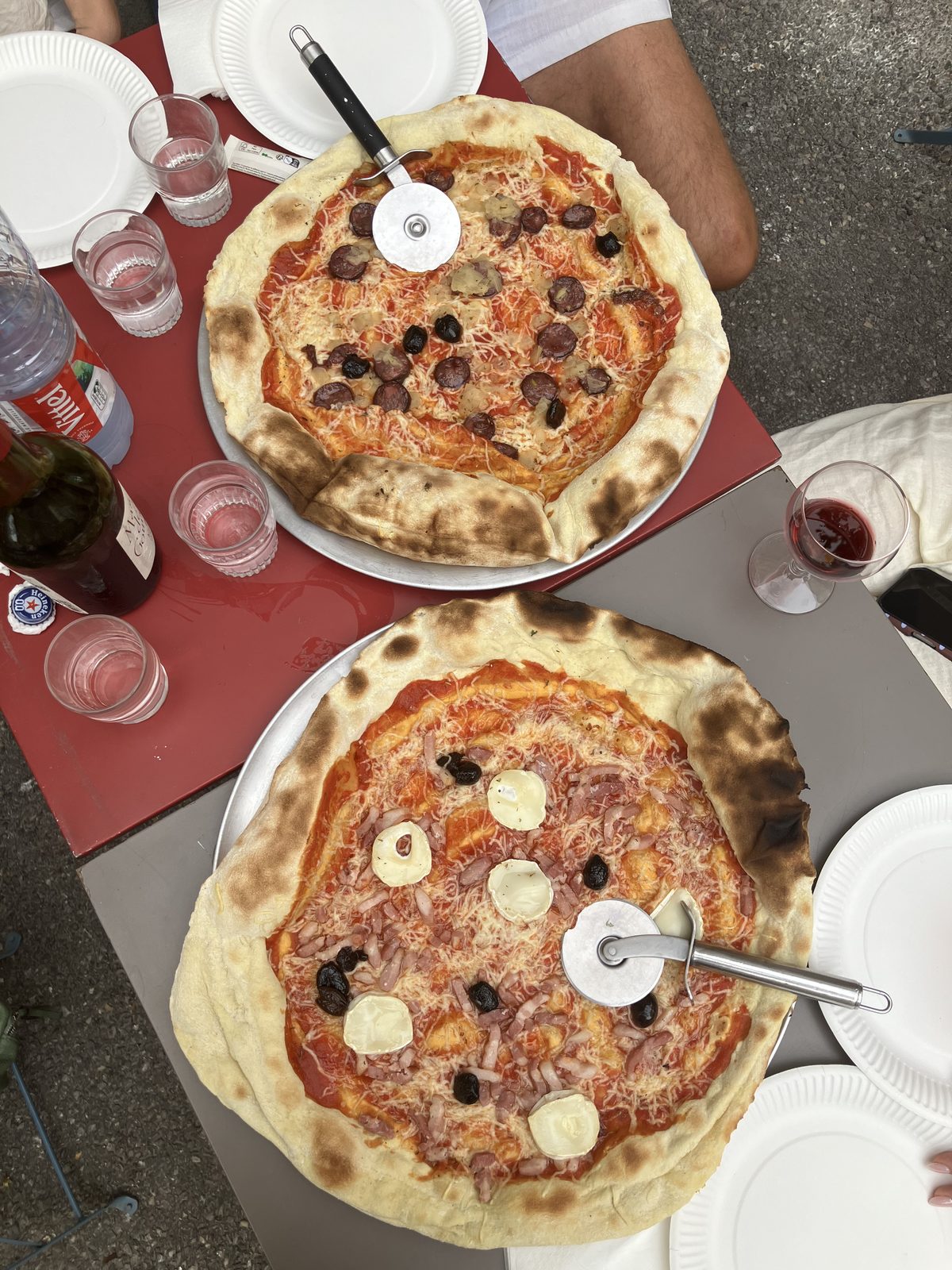 Two large pizzas on a red table in the village