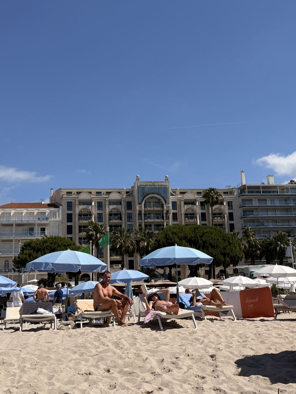 The beach at Cannes with blue umbrellas and the grand facades behind