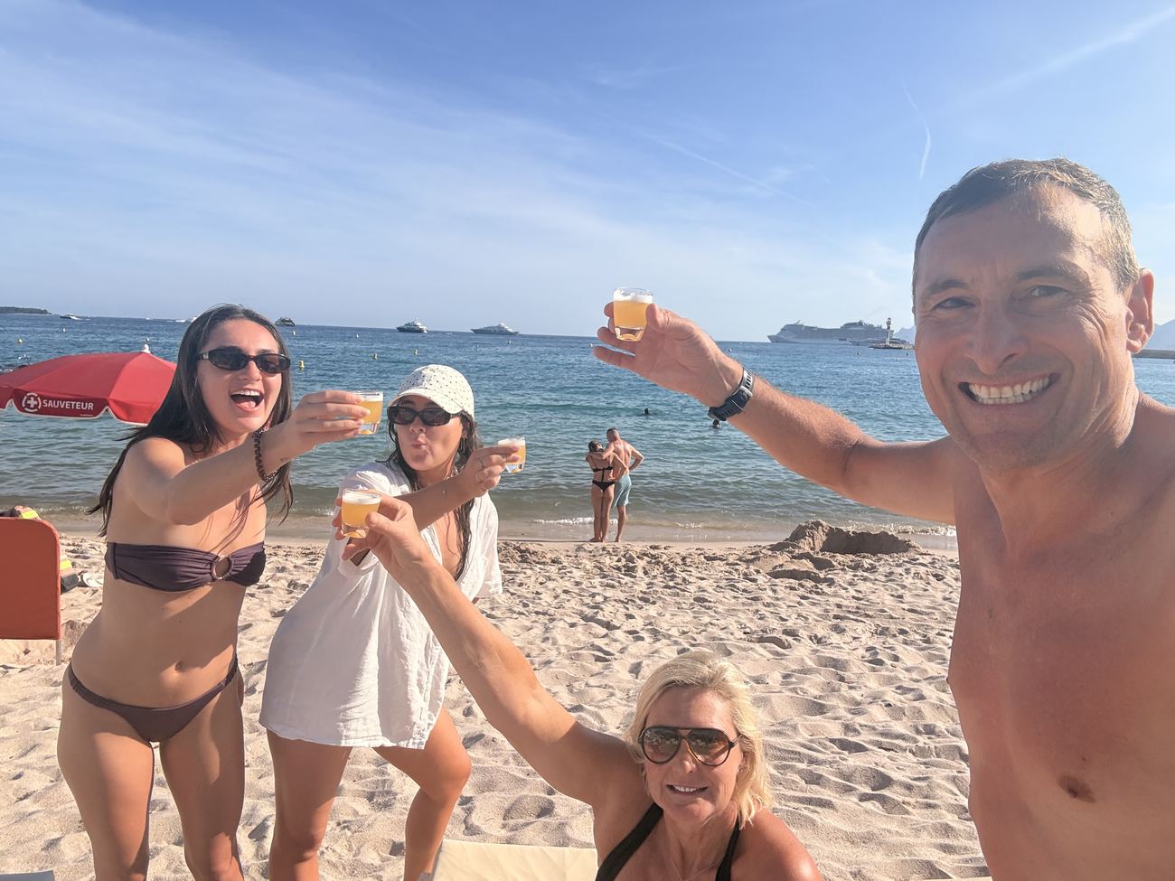 Four of the family standing waist-deep in the sea at Cannes, raising drinks