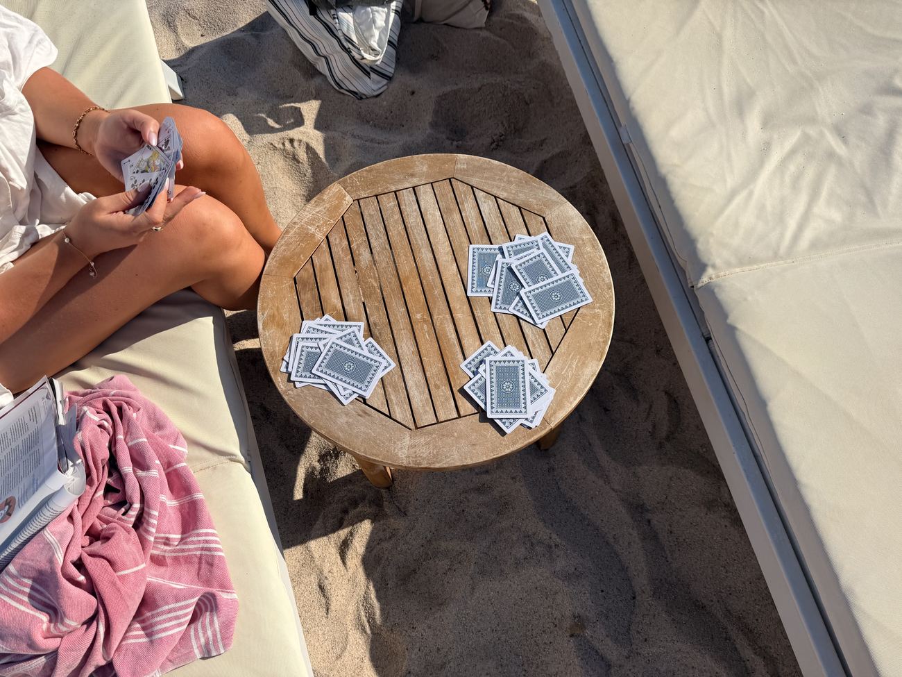 A round table on the beach with playing cards and drinks