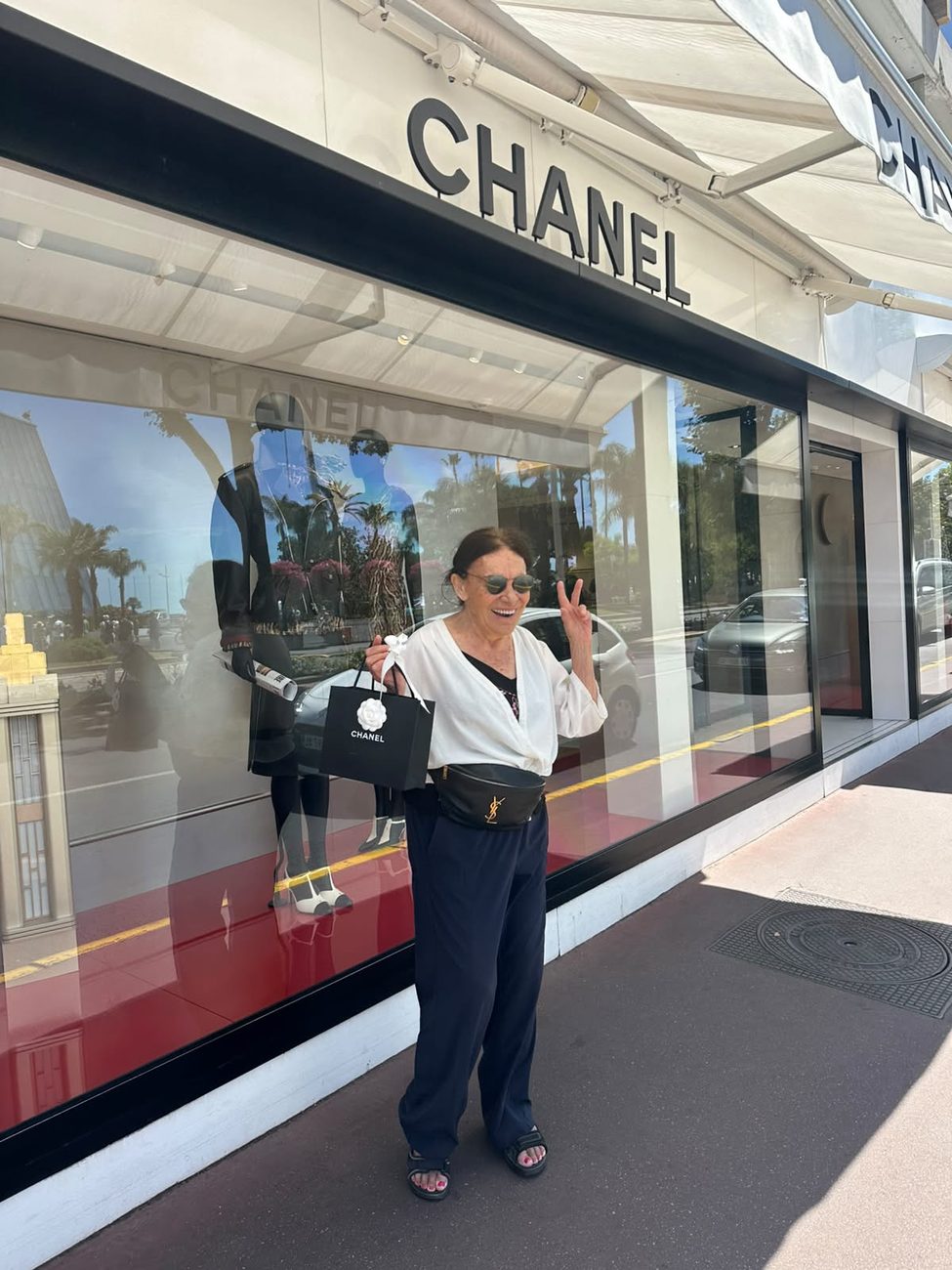 Maman outside the Chanel boutique in Cannes, wearing her new sunglasses and holding the shopping bag, giving a peace sign