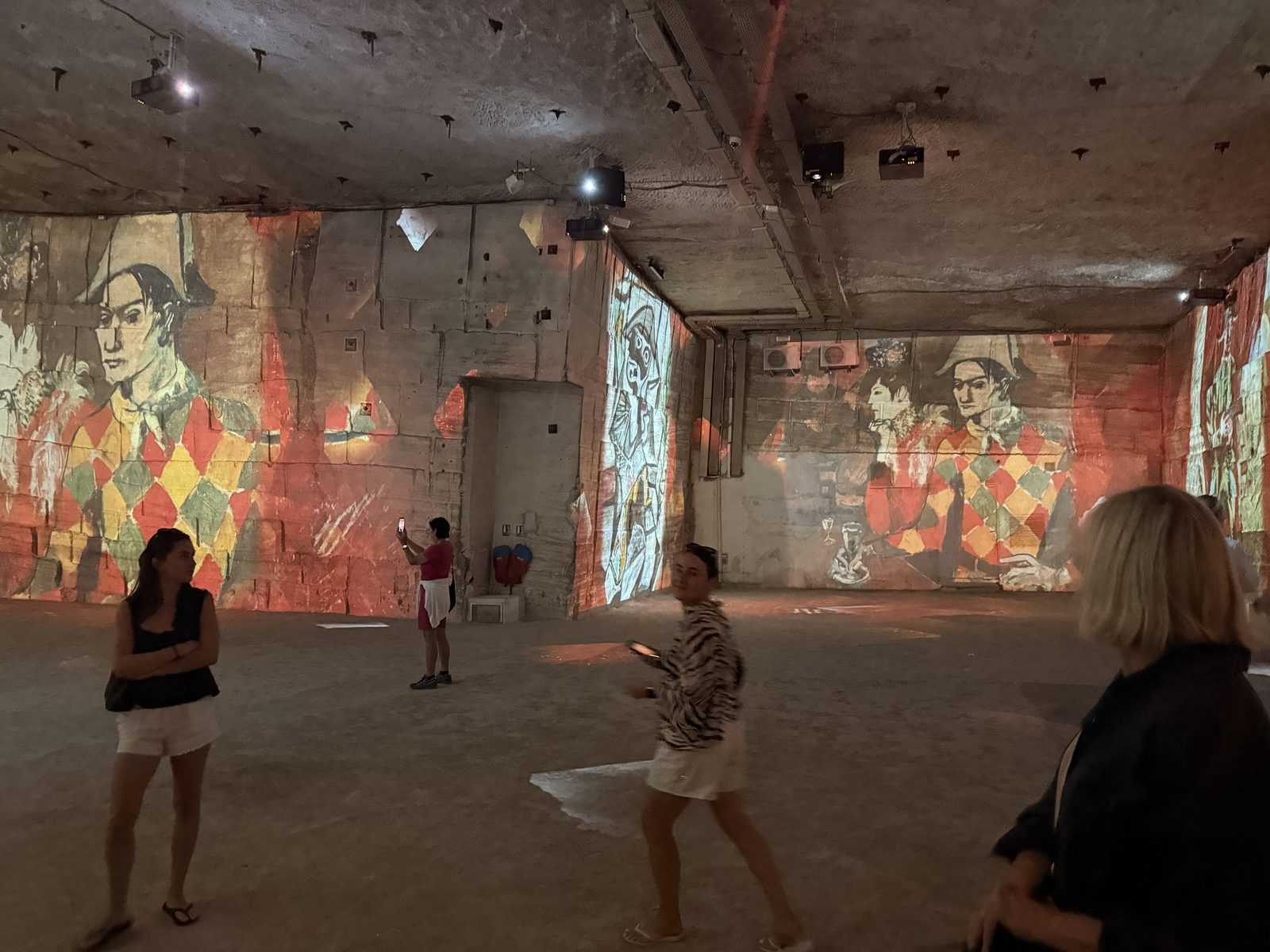 A wide quarry chamber with figures dwarfed by projected paintings