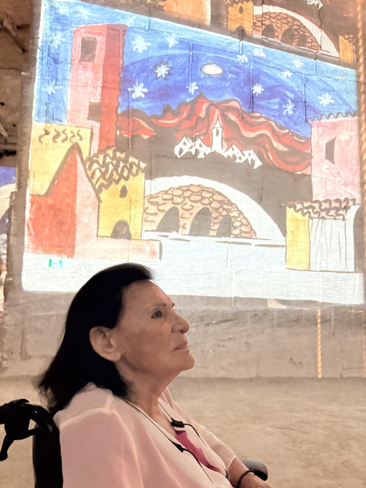 Maman looking up into a projected Picasso sky in the quarry