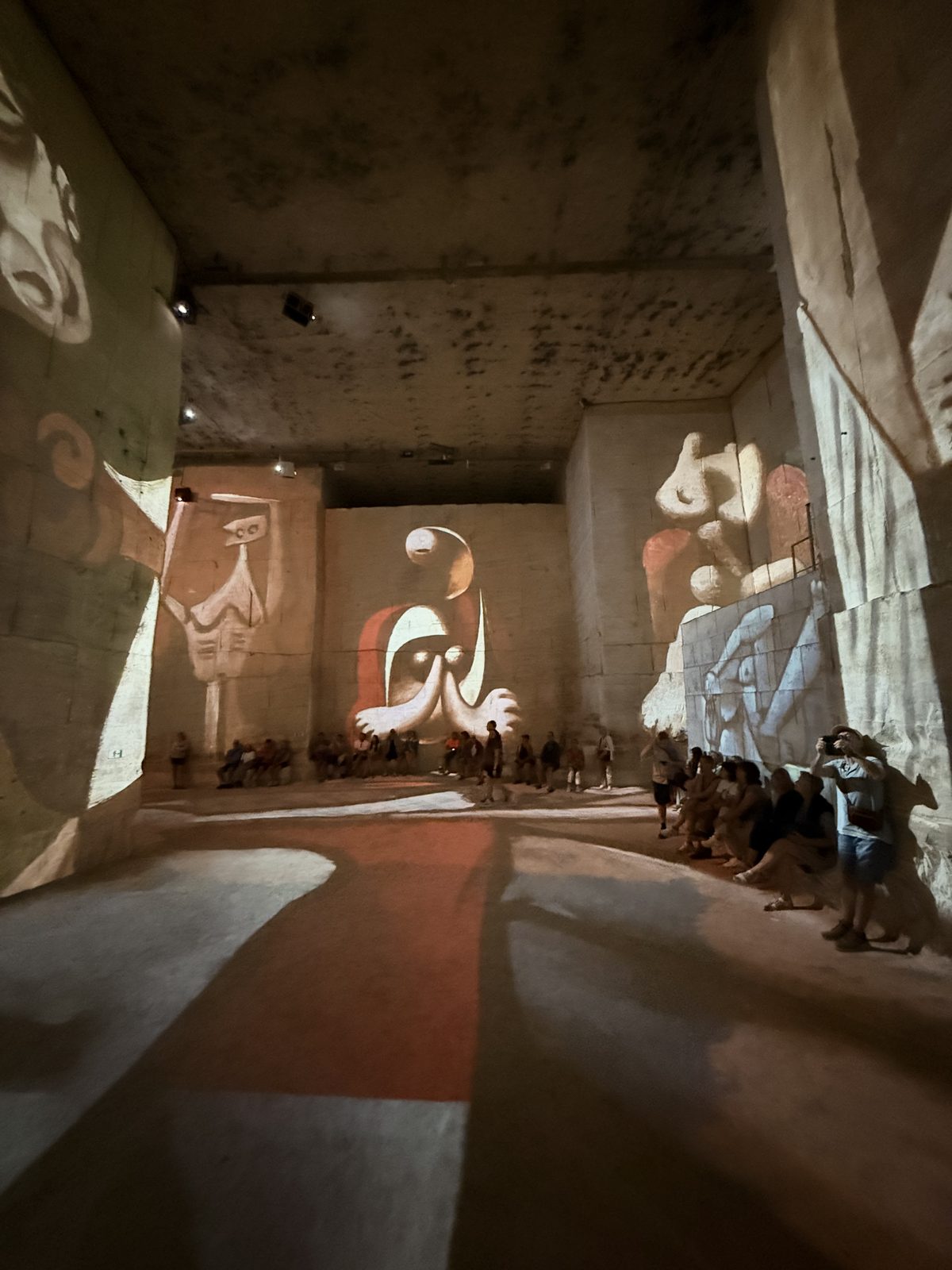 The vast quarry chamber at the Carrières des Lumières with Picasso works projected across the stone walls and floor