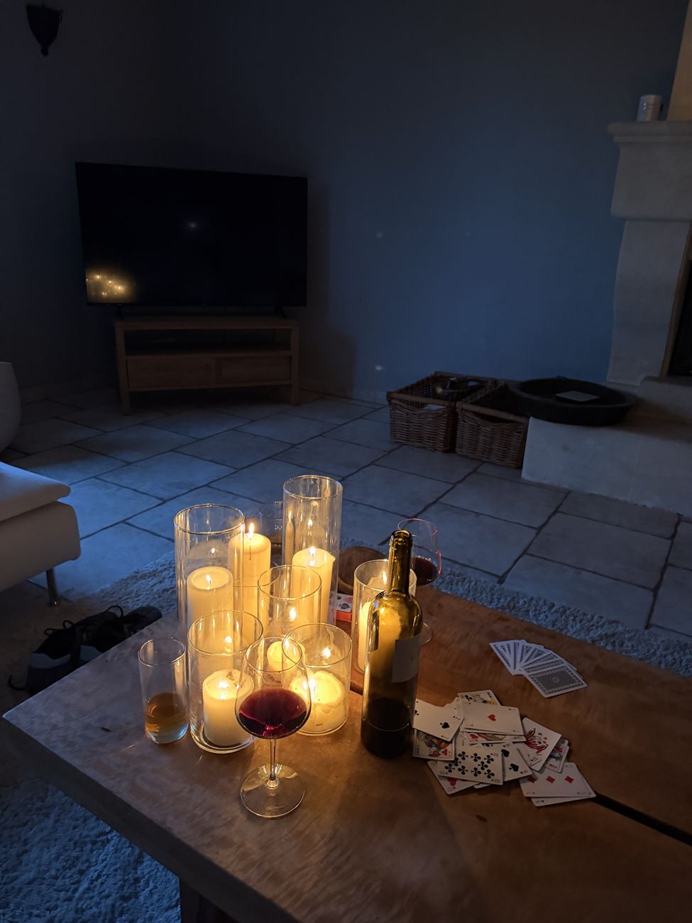 A candlelit table at dusk on the stone terrace of the mas, a glass of wine and a bottle, the last evening