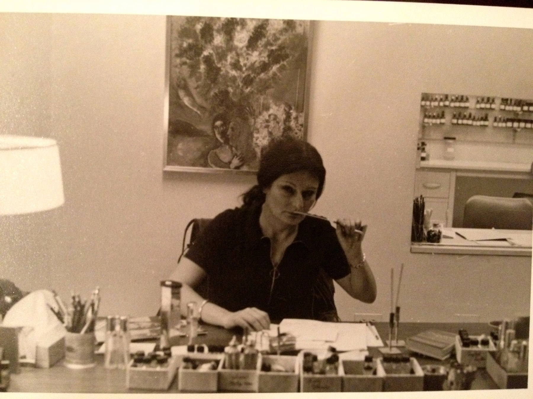 Maman at a laboratory bench with trays, pipettes and a notebook, a painting on the wall behind