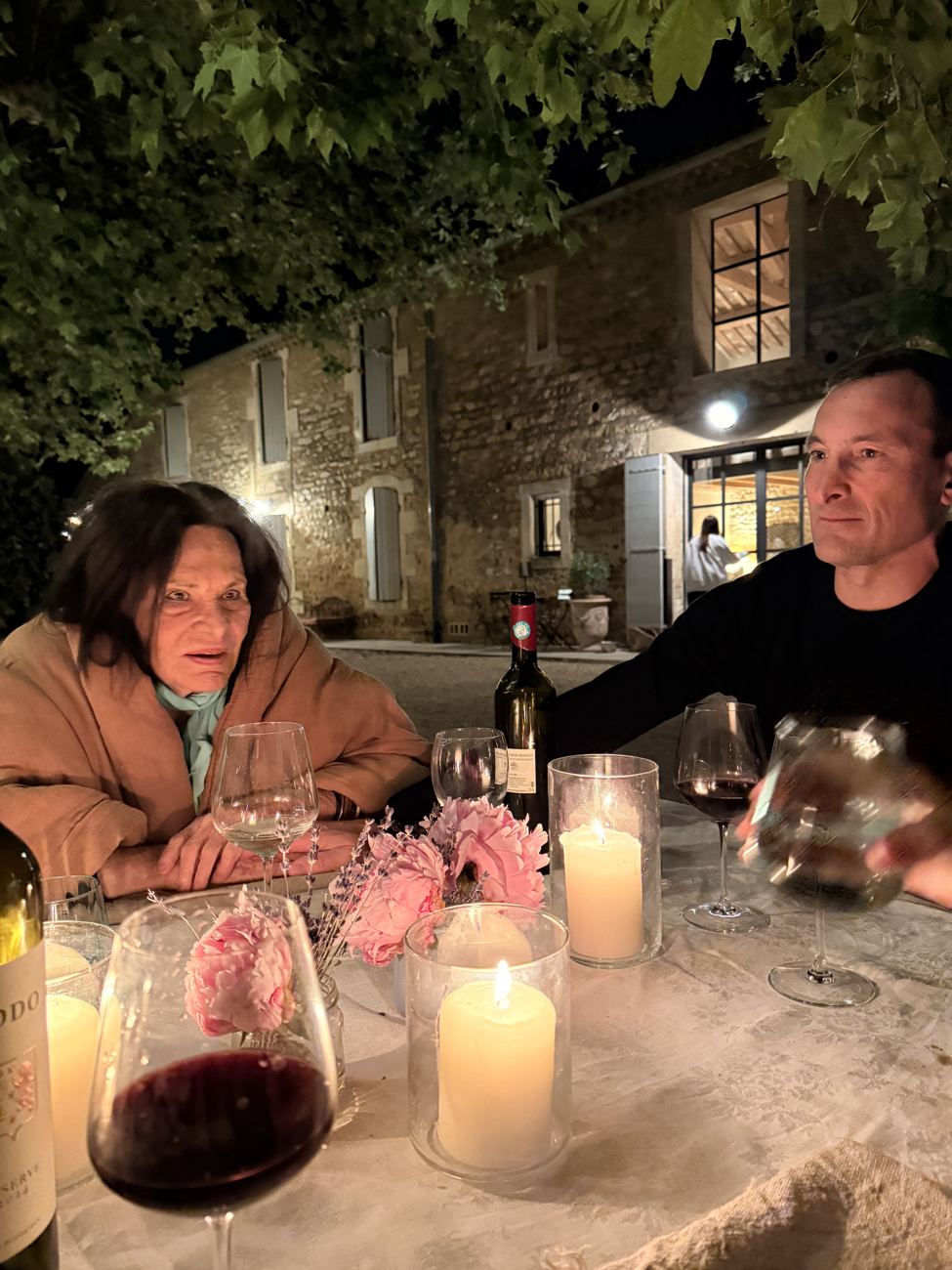 A couple at the candlelit table, wine glasses catching the flame