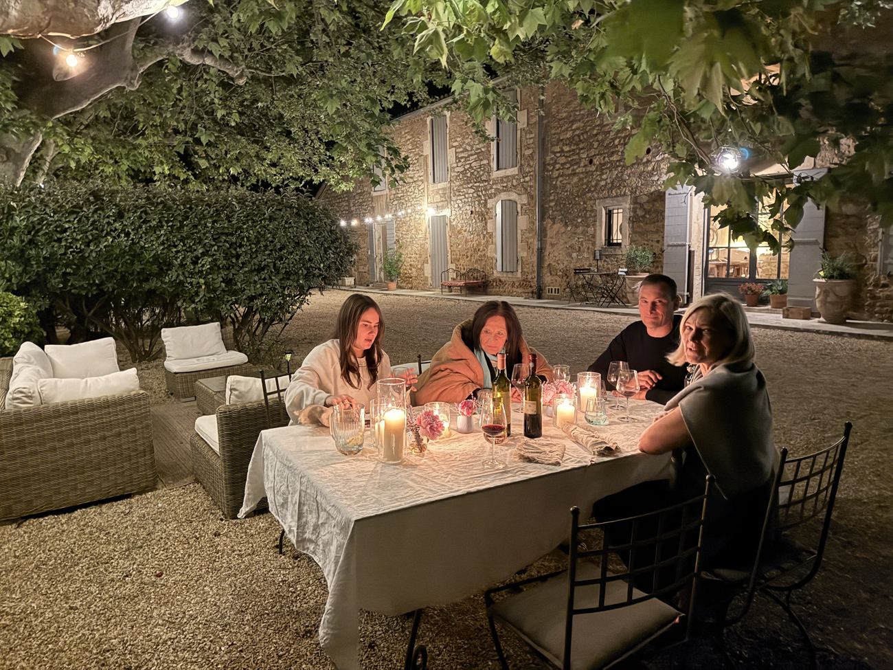 The long candlelit dinner table at night, the lit stone mas glowing behind