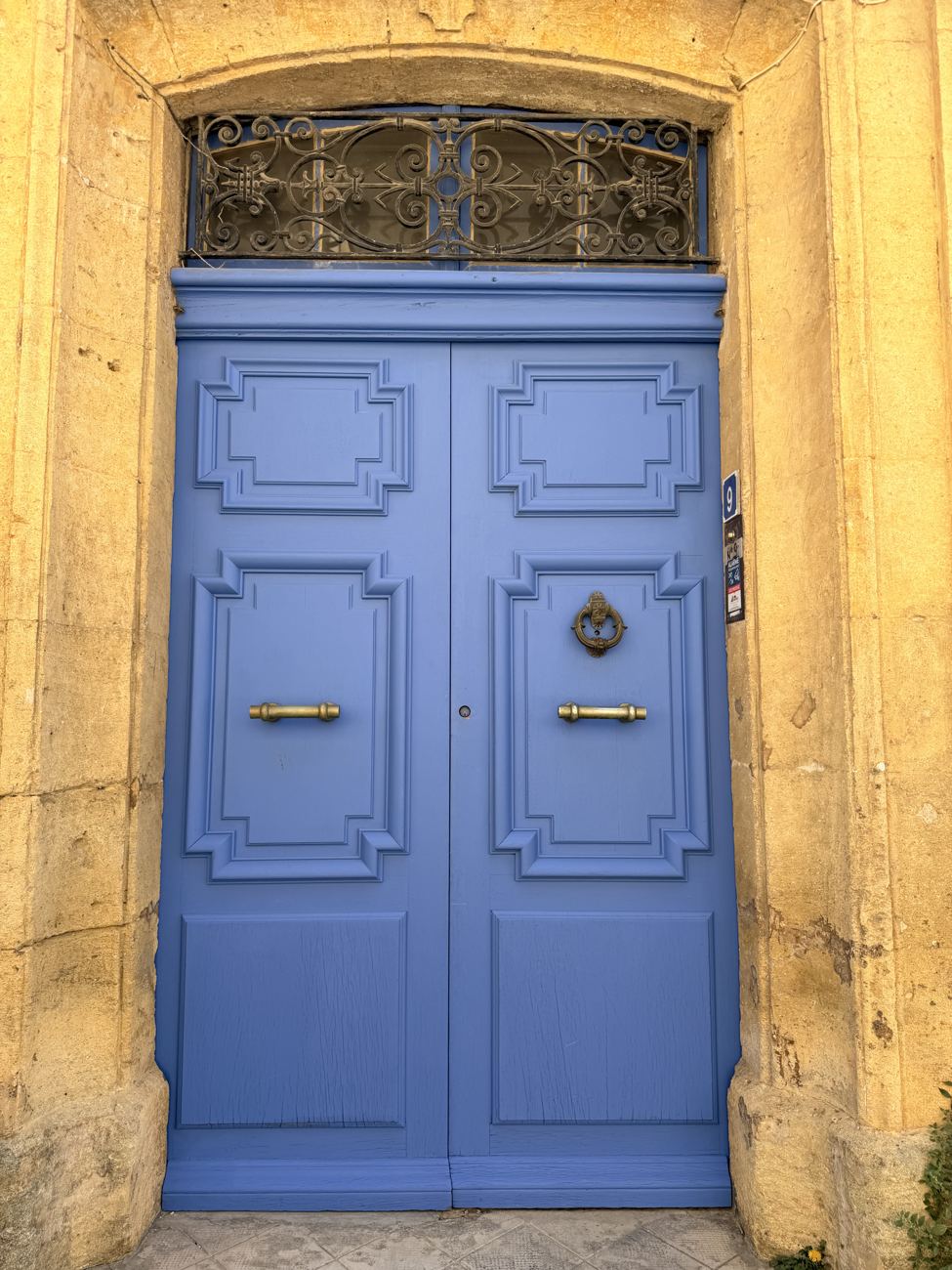 A tall lavender-blue Provençal door set in honey-coloured stone