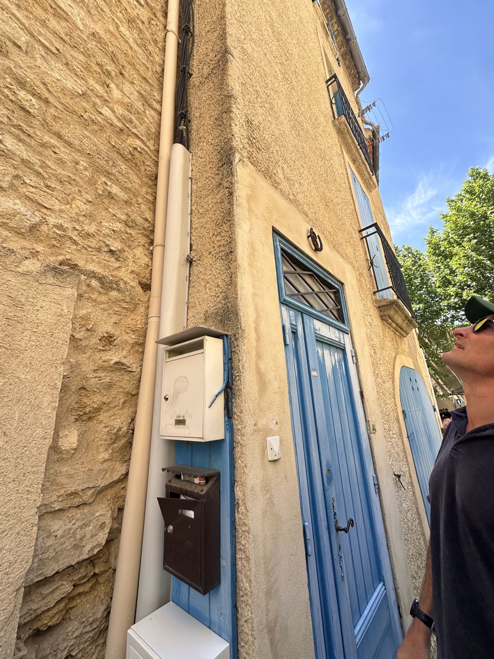 A narrow shaded alley between stone houses with a blue door